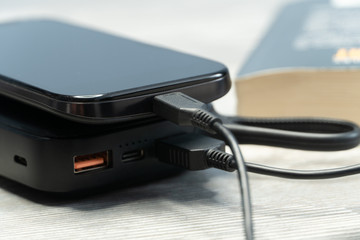 Charging smartphone with a external power energy bank. Power Bank is connected to a smartphone.