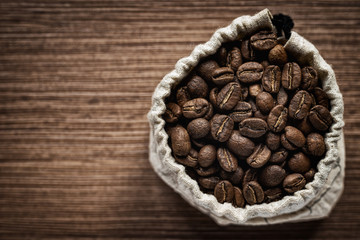 Top view coffee beans in a bag on a wooden board.