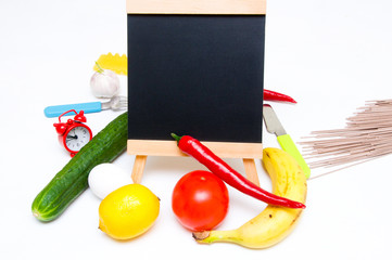 Copy space. Slate, tomatoes, banana, red paper, lemon, egg, fork, clock, knife, pasta, garlic and cucumber on white background. Cooking at home. Cooking. Vegetables and fruits. . Ingredients. Recipe 