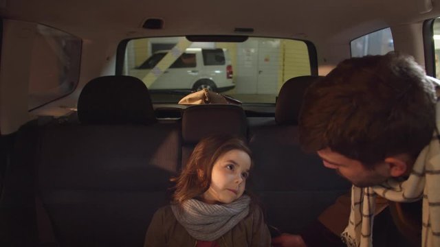Dad takes a sleeping daughter out of the car