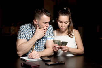 A man sadly looks at a woman who considers modest monetary savings