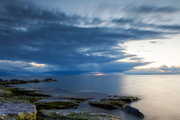Obraz premium Coastal landscape with rain clouds in background during sunset
