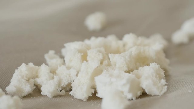 Organic latex pieces fall down onto cloth background in slow motion