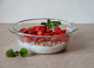 Muesli with yogurt and strawberries in a glass bowl.