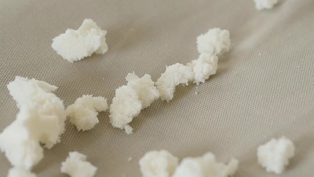 Organic latex small piece fall like rain in slow motion on cloth background.