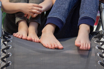 children with children's bare feet sit on a chaise longue. a boy and a girl are resting in the sun....