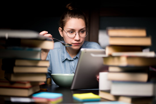 A student girl eats and rests from study - she watches the series on the tablet