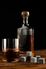 Glass of Irish whiskey with glass bottle over dark background.