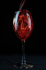 Fototapeta na wymiar Wine. Red wine pouring into a wine glass. Isolated on black background. Border art design