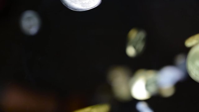 Pile of Saudi Riyal coins fall on the camera directly from black background