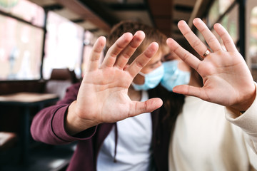 Couple wearing protective medical masks,show stop gesture,hand NO sign,people against from Covid-19