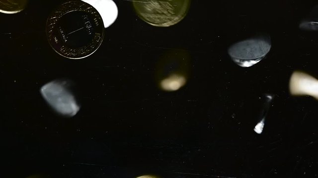 Pile of Saudi Riyal coins fall on the camera directly from black background