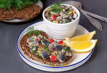 Polish Pickled Herring in Oil. Open sandwich with sliced fish and apple-onion relish on rye toast bread with seeds.