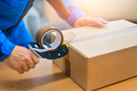 Worker Hands Holding Packing Machine And Sealing Cardboard Or Paper Boxes