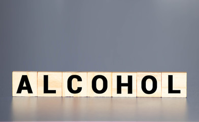 Alcohol,text word title caption label cover backdrop background. Alphabet letter toy blocks on black reflective background. White alphabetical letters. White educational toy block with words on mirror