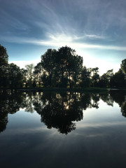 Fototapeta na wymiar trees and cloudy sky are mirrored in the lake