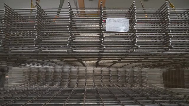 The workshop for the production of reinforcing mesh. A lot of rebar mesh folded for loading. A tutu of rebar mesh is lifted by a crane