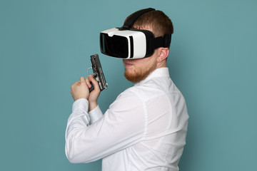 a front view young man in white t-shirt with gun playing vr on the blue background