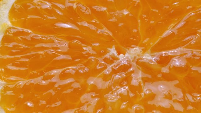Squeezing a fresh and juicy orange. Extreme close up.