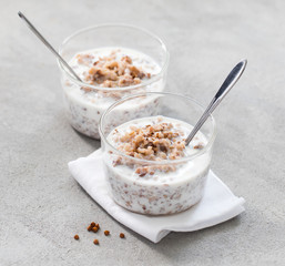 t of cereals boiled buckwheat with milk in a glass Cup on a light gray background