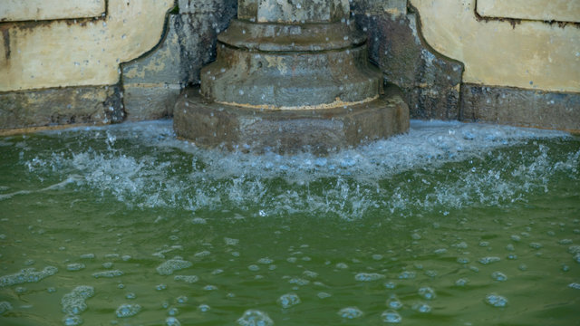 Close-up on the nets of water flowing along a stone fountain, to pour into the basin