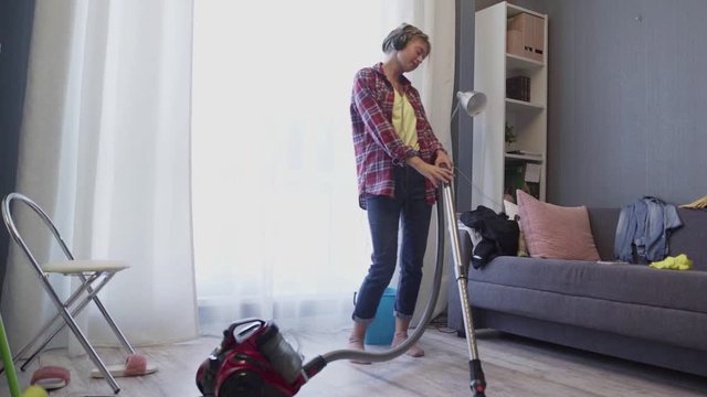 Young woman using a vacuum cleaner to the floor