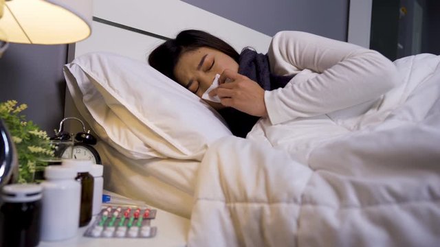 sick woman feeling cold and sneezing in bed