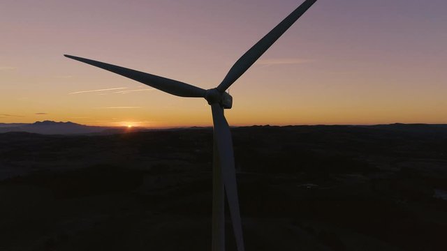 AERIAL DRONE CLOSE UP ORBIT OF WIND TURBINE BLADES SPINNING WITH SUNSET 