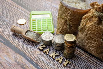 ZAKAT word,  coin stacked ,  calculator ,  and rice  on wooden background.