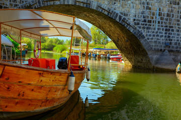 Fototapeta na wymiar wooden touristic boat at water canal in the medieval town Virpazar from Montenegro 