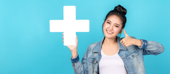 Banner of asian woman smiling, showing plus or add sign and thumb up on blue background. Cute asia girl wearing casual jeans shirt and showing join sign for increse and more benefit concept - obrazy, fototapety, plakaty