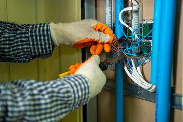 Young repairman fixing electrical,Electrician checking wires in electrical box with pliers in...