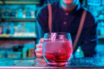 Close up of alcoholic cocktail, beverage, drink, prepared by professional barman in multicolored neon light. Entertainment, drinks, service concept. Modern bar, trendy neoned colors, copyspace.