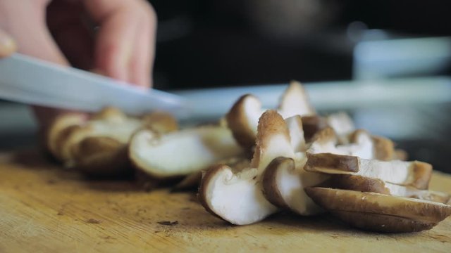 Сook cuts shiitake mushrooms at home on  wooden desk  kitchen table