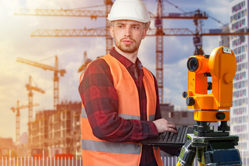Surveyor at the construction site. A bearded man stands next to theodolite against the backdrop of...