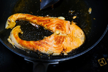 Fried salmon steak with galic on black pan
