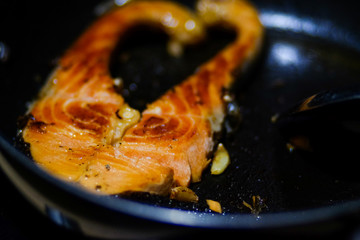 Fried salmon steak with galic on black pan