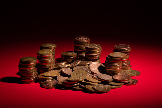 Close up stacks of GBP sterling one pence coins, highlighted on a spot lit red background.