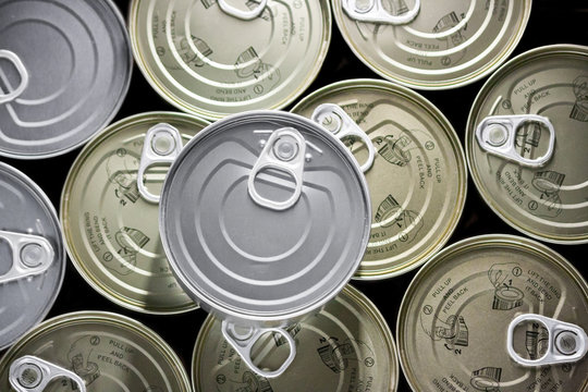 flat bottom filled with cans of golden tuna and a tin on a silver plate.