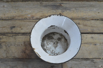 pot de chambre en émail blanc vintage sur un plancher de vieux bois