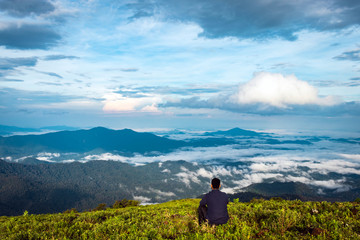 Fototapeta premium man isolated feeling the serene nature at hill top with amazing cloud layers in foreground