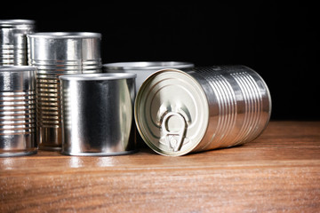 various sizes of silver color canned products from left side on brown wood and dark background