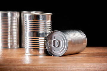 Various cans of food product with easy open silver color on a wood and dark background