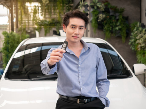 Asian Young Attractive Man Standing Near A Car At The Dealership And Showing Car Keys.