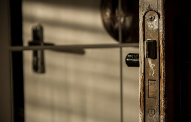 Old handle with a lock in a white door, reflected in the mirror. Peeling paint. Pleasant light in the interior.