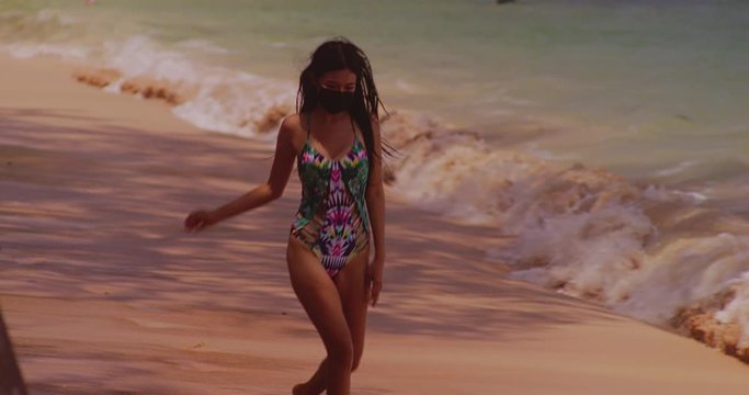 sexy girl wearing facemask running on a tropical sandy  beach