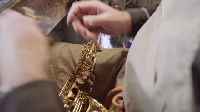 Skilled instrument maker repairing keys of golden saxophone body by hand