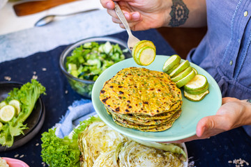 Woman hands hold vegetables on plate. Vegan healthy food. Herbs flatbread tortilla with zucchini.