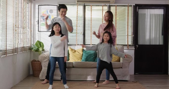 Asian family listening music dancing jumping together. They having fun in modern living room enjoying leisure lifestyle at home together.
