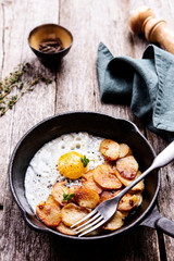 Fried Eggs and Potatoes in cast iron skillet on rustic wooden table. Skillet Breakfast. Selective focus